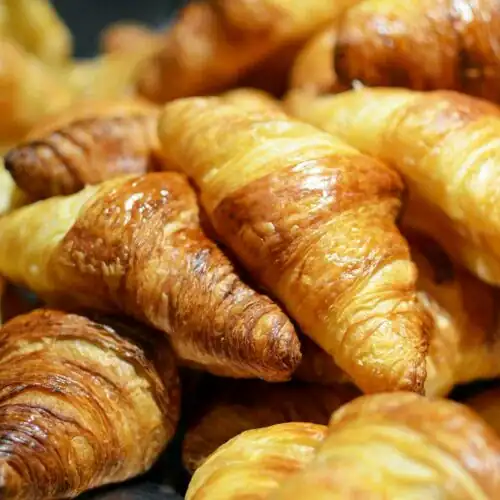 Golden, flaky croissants stacked together, showcasing their buttery layers.