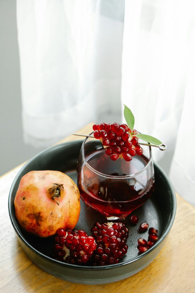 pomegreate and a glass of pomegrenate juice reduction in a plate