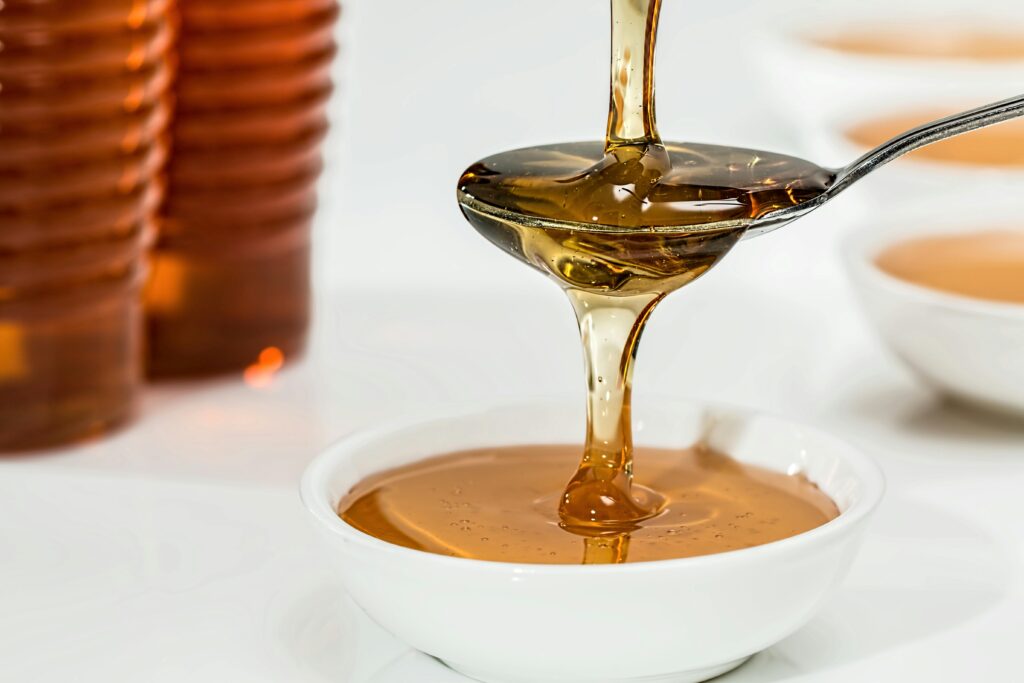 pouring maples yrup in a bowl through a stainless spoon