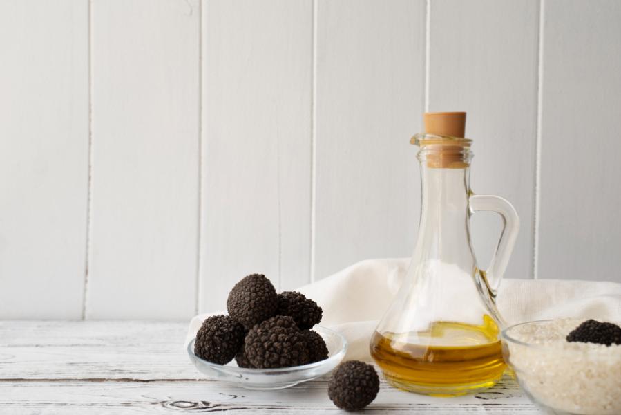 raw truffle in a bowl and oil olive in a bottle with grey background