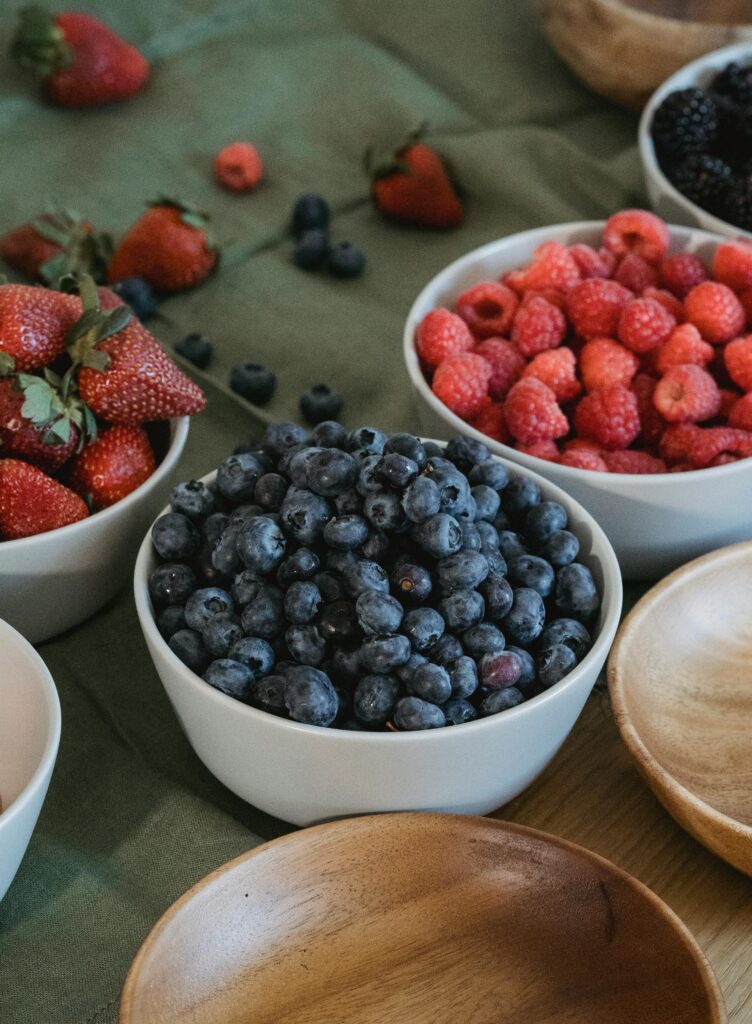 strawberries, blueberries and raspberries in bowls 