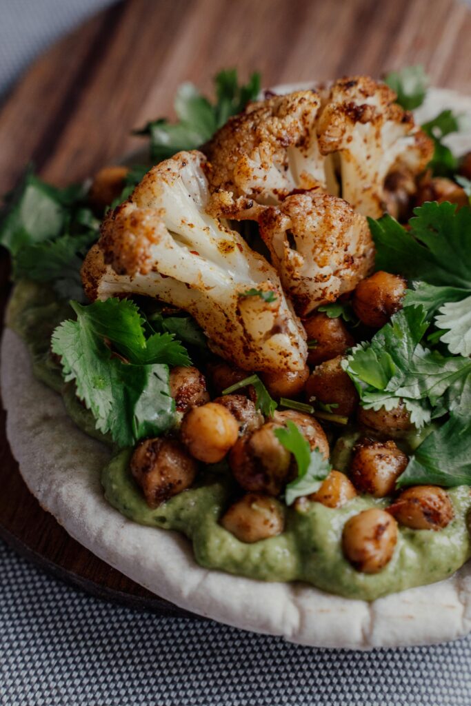 A bed of Avocado Sauce on Bread and Chickpeas and Coliflower and Herbs