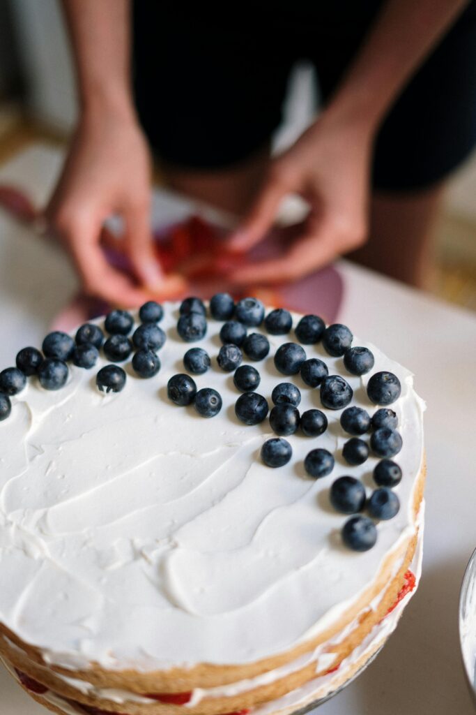 two female hands garnishing french toast souffle with blue berries