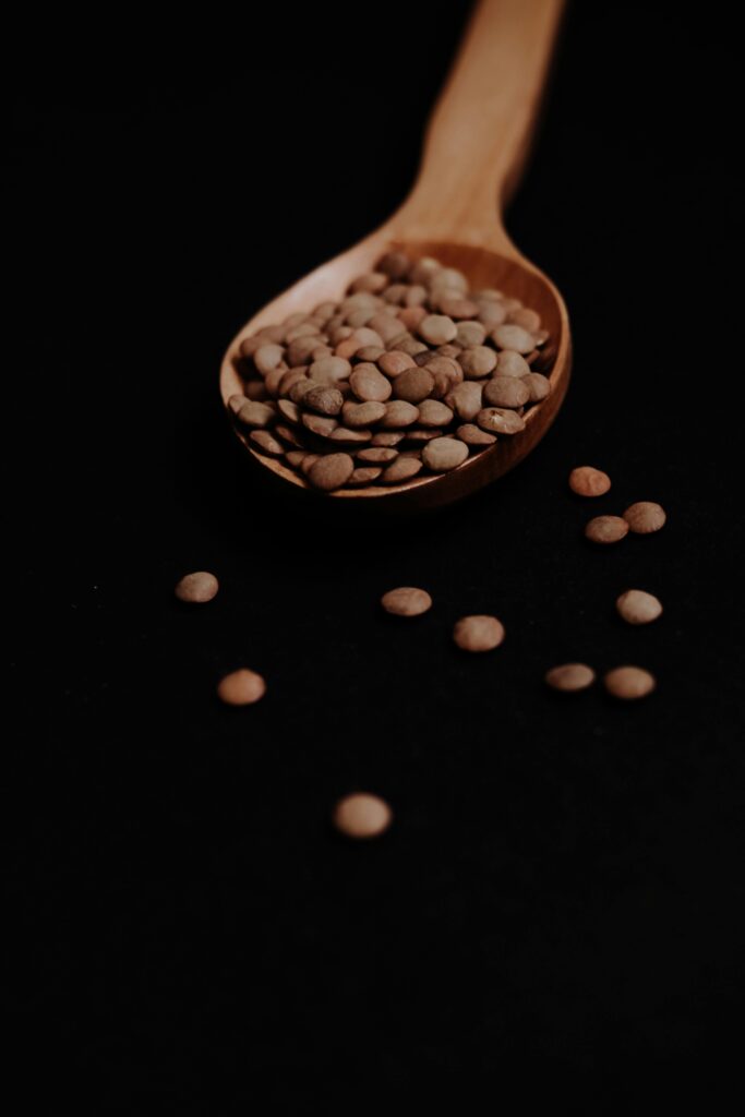 Lentils in a Wooden Spoon with a Black Background