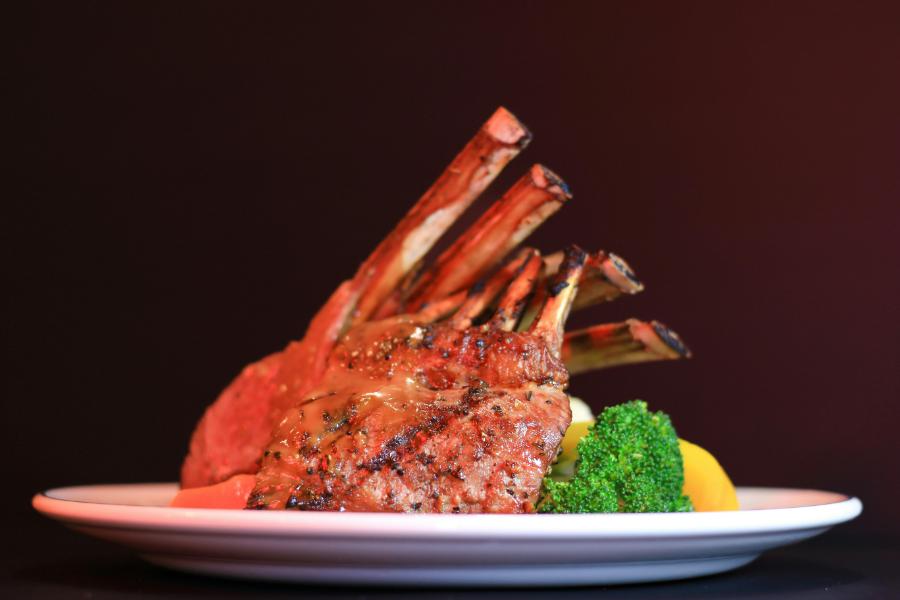 Rack of Lamb garnished with herbs and served in a white plate