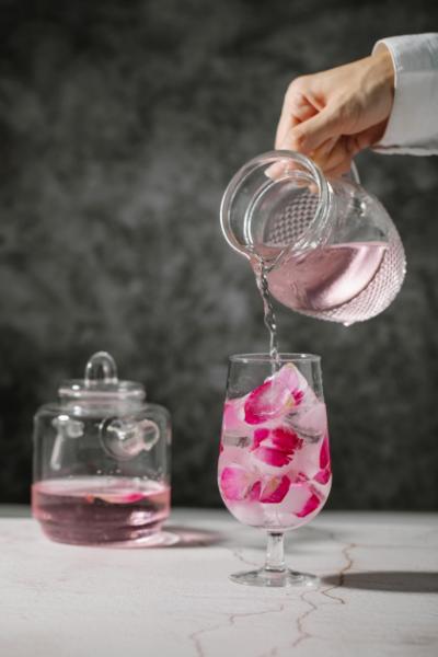 pouring rosewater in a glass from a jar