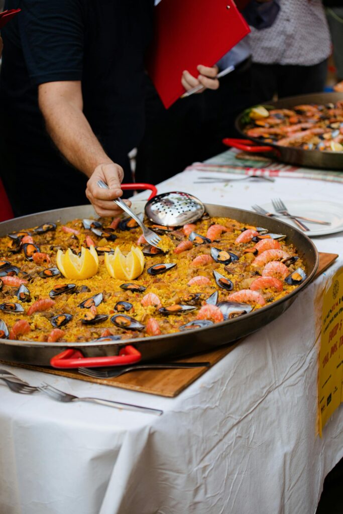 A Big pan Of Seafood Paella with a man digging in with a fork