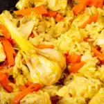 A vibrant dish of rice cooked with leftover turkey, sliced carrots, garlic, and spices, creating a flavorful and aromatic meal.