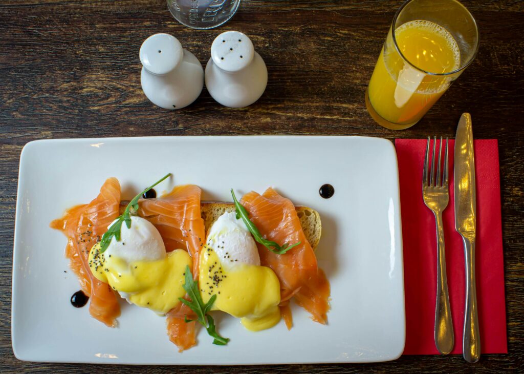 salmon benedict foam in a white rectangular white plate and a glass pf orange juice