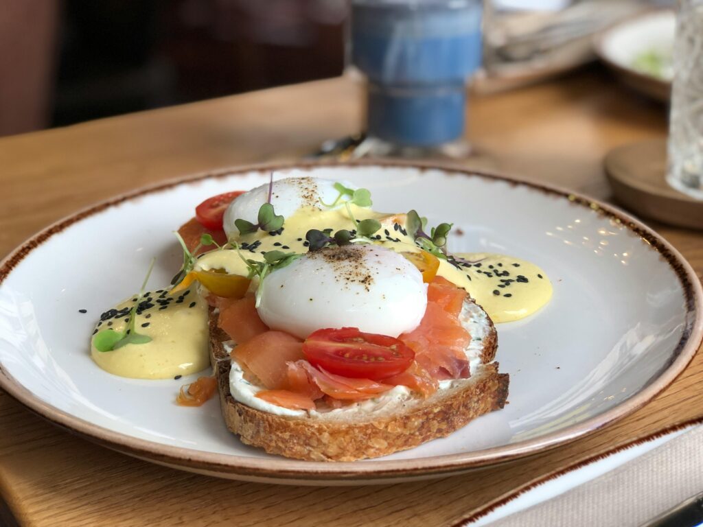 Egg benedict topped salmon put on a slice of bread and served in a white plate