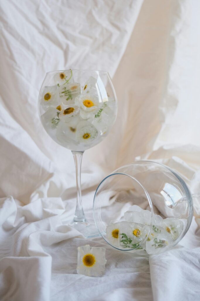 stemmed glassware with flowers in it and a white background