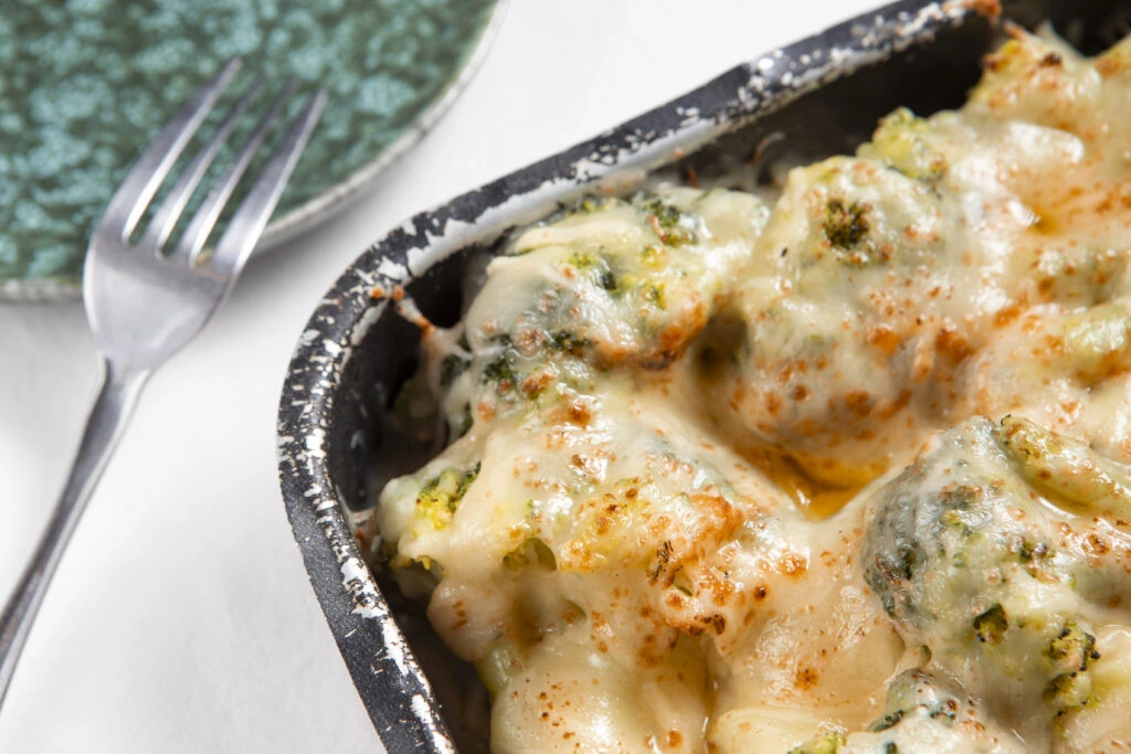 Broccoli chicken rice casserole topped with golden melted cheese in a white baking dish