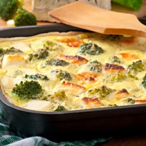 A golden-brown broccoli chicken casserole topped with melted cheese, served in a white baking dish with a sprinkle of fresh herbs.