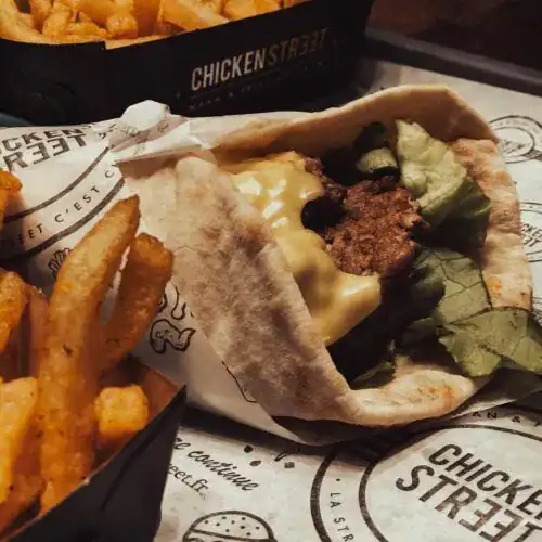 A lamb gyro wrap with melted cheese, lettuce, and pita bread served alongside crispy seasoned fries.