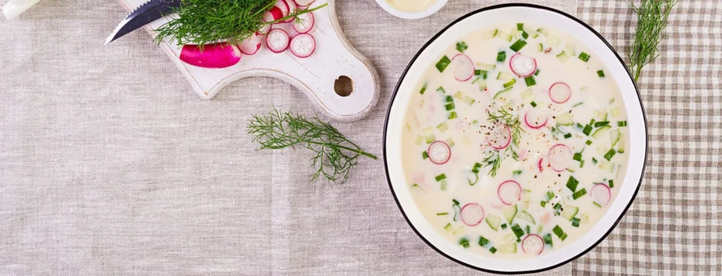 Refreshing radish and cucumber cold soup in a white bowl with fresh herbs