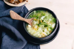 Rustic radish soup in a black bowl with wooden spoon