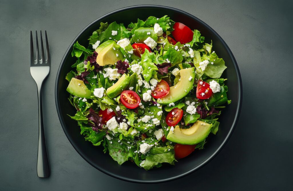 Fresh arugula salad with cherry tomatoes, feta cheese, and avocado in a modern bowl