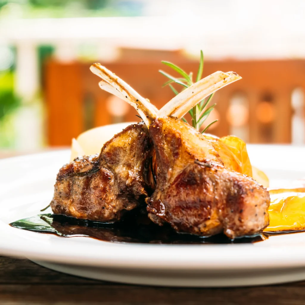 Succulent lamb chops seasoned with garlic and rosemary, beautifully seared to golden perfection and garnished with fresh herbs on a rustic wooden board