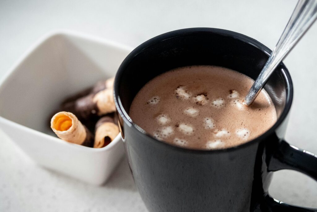 hot chocolate in a black cup with a spoon in it