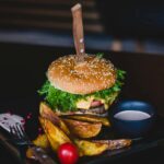 lamb burgers with mint yogurt sauce along with french fries in a black plate