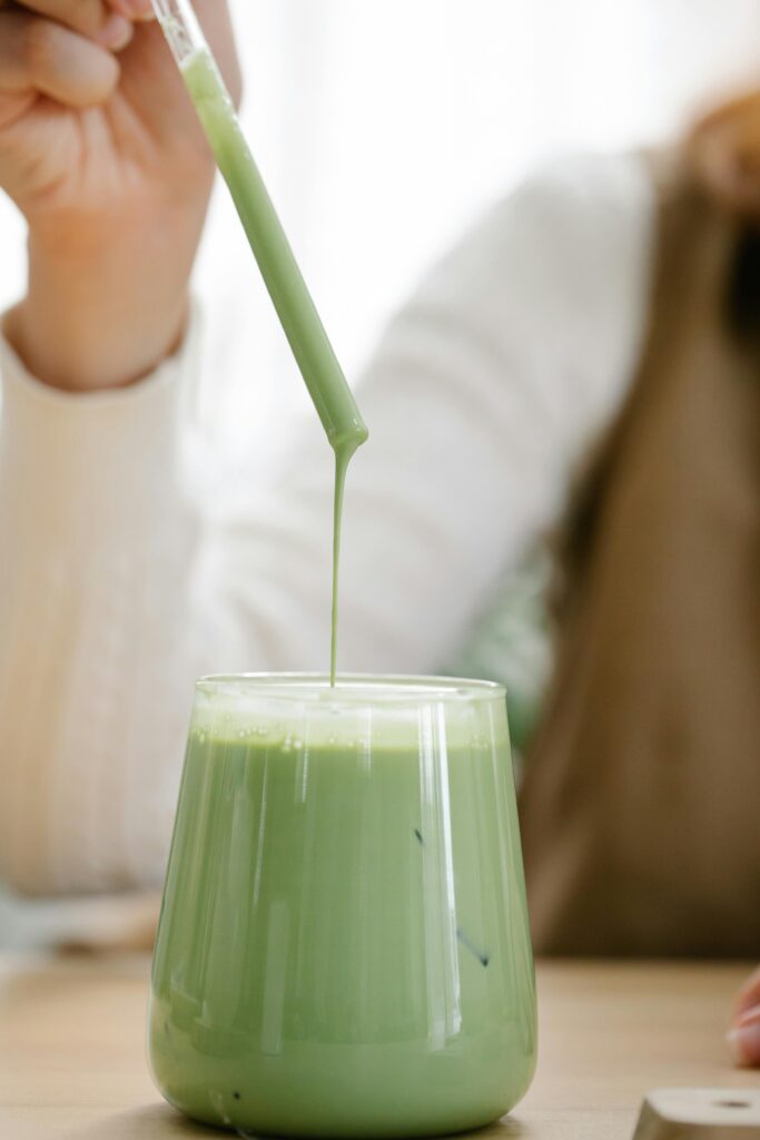 matcha latte with a lady`s hand holding a straw