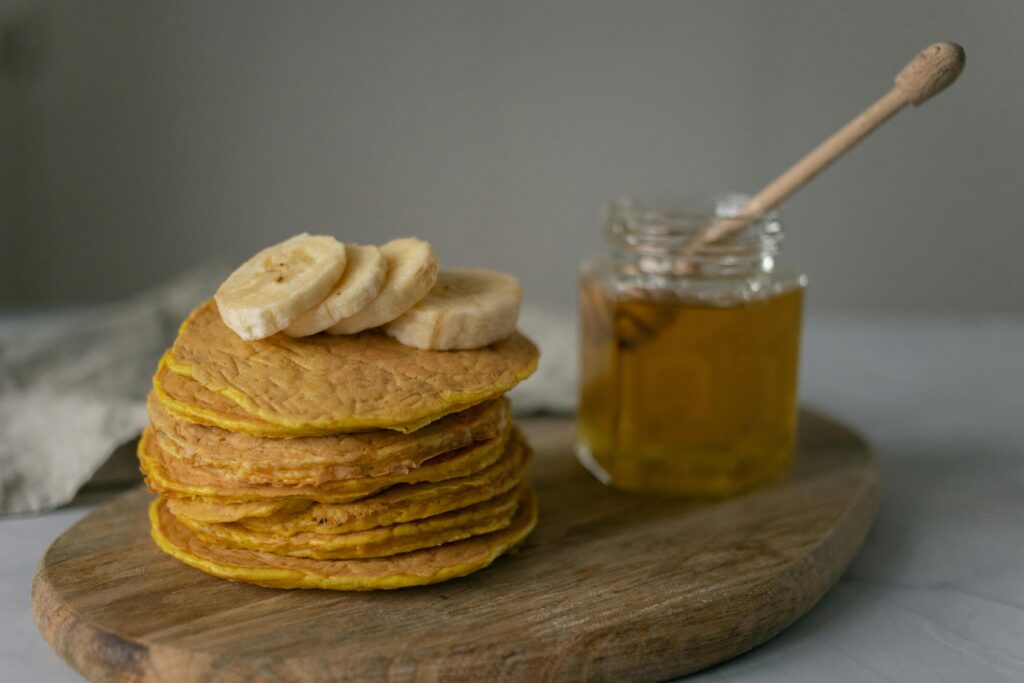 pankake garnished with slices of banana and a jar of honey