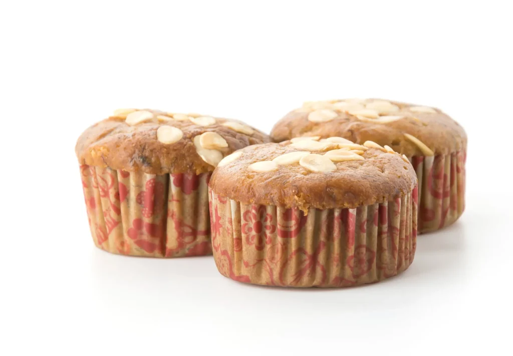 Three banana oatmeal muffins topped with almond slices, placed against a clean white background.