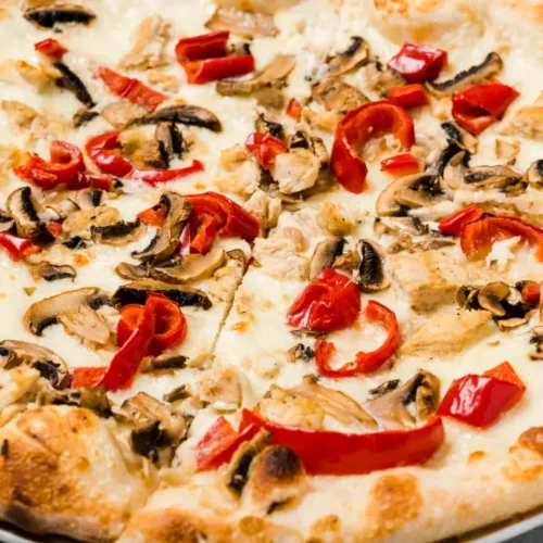 A freshly baked mushroom pizza topped with sautéed mushrooms, roasted red peppers, and melted cheese on a golden, crispy crust.