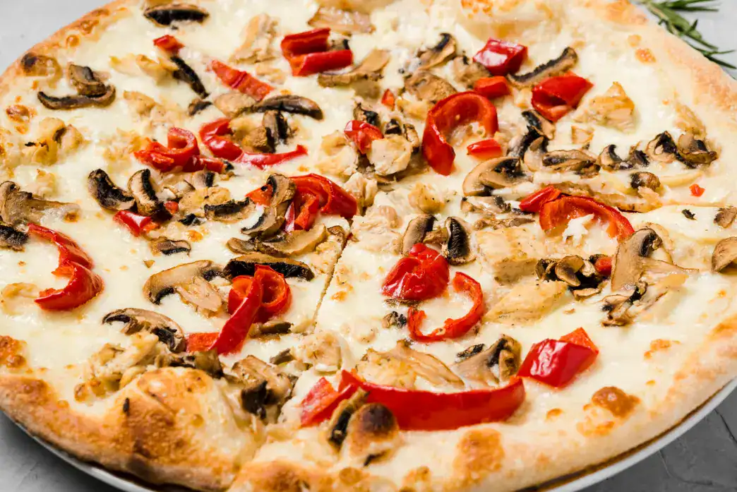 A freshly baked mushroom pizza topped with sautéed mushrooms, roasted red peppers, and melted cheese on a golden, crispy crust.