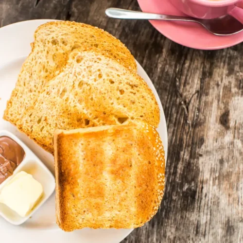 Toasted bread served with butter, chocolate paste, and a cup of coffee on the side.