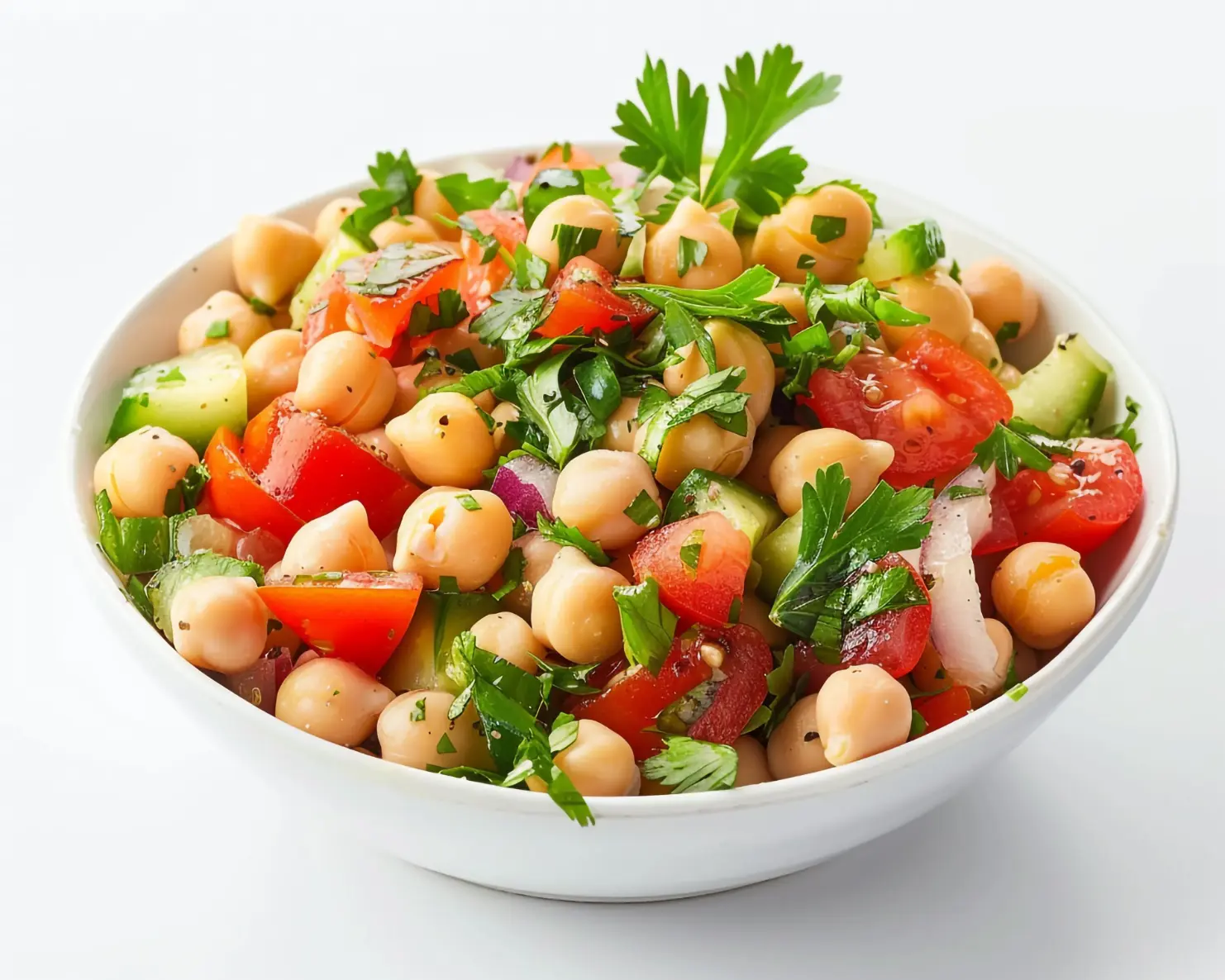 A bowl of fresh chickpea salad with chopped tomatoes, cucumbers, red onions, and parsley, dressed lightly with olive oil and herbs.