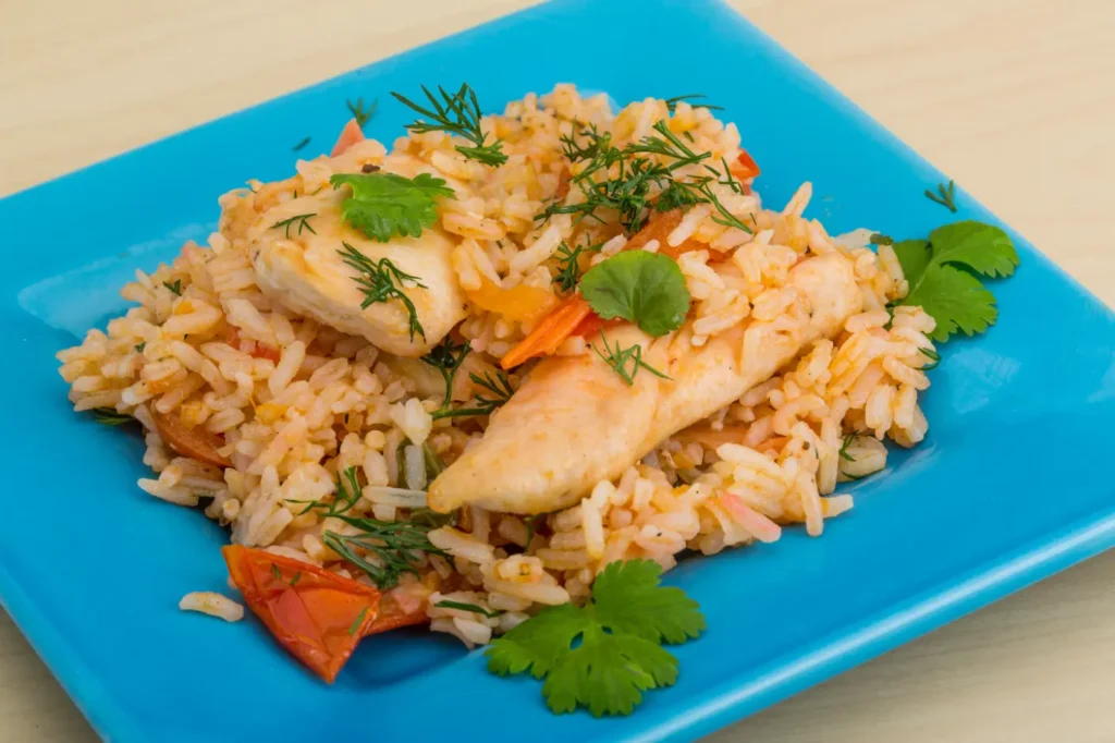 A vibrant plate of fried rice with chicken, garnished with fresh dill and cilantro, served on a bright blue plate.