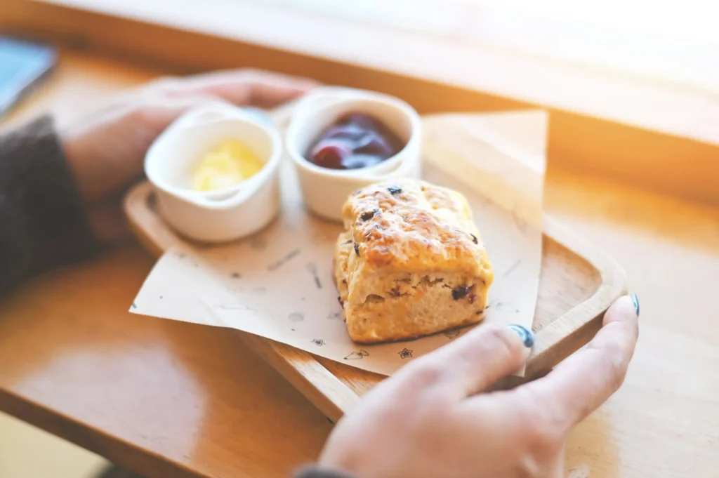 Traditional English scone with jam and butter served on a wooden tray