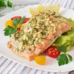 Baked salmon fillet with almond and herb crust served over mashed avocado with cherry tomatoes