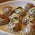 A plate of homemade Swedish meatballs covered in a rich, creamy gravy, garnished with fresh parsley.