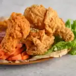Crispy homemade fried chicken served with sliced carrots, lettuce, and dipping sauce