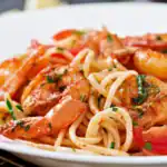 Shrimp scampi with linguine pasta, cherry tomatoes, and fresh herbs served on a white plate