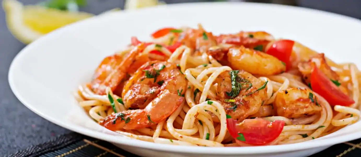 Shrimp scampi with linguine pasta, cherry tomatoes, and fresh herbs served on a white plate