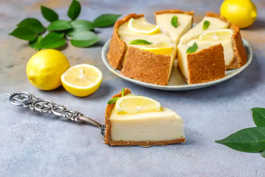 Slice of lemon ricotta cheesecake garnished with lemon and mint on a rustic background.