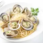 Plate of clam linguine pasta garnished with parsley on a white background