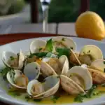 Clams in garlic butter sauce garnished with parsley and served on a white plate