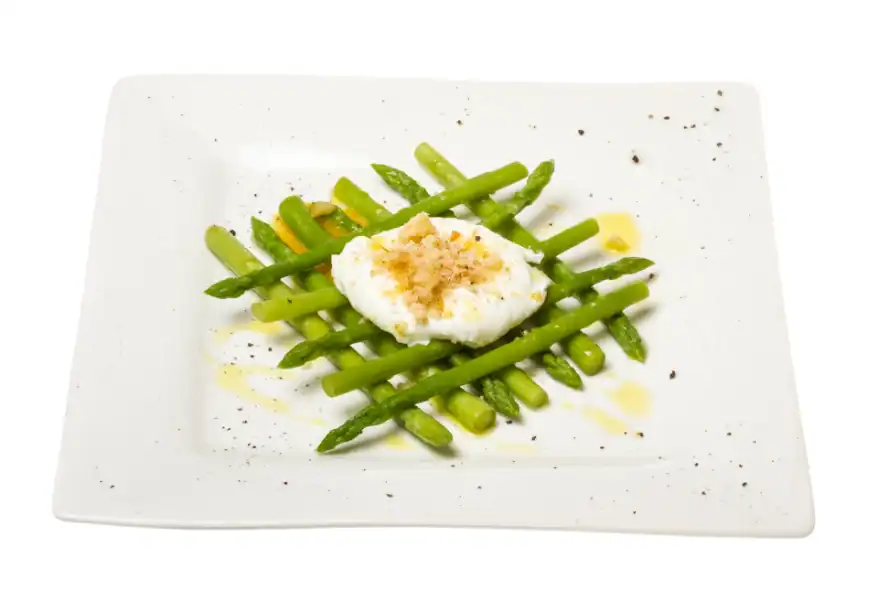 Steamed asparagus spears served with a poached egg and crispy croutons on a white plate.