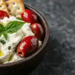 Whipped ricotta cheese dip topped with olives, herbs, and served with crackers