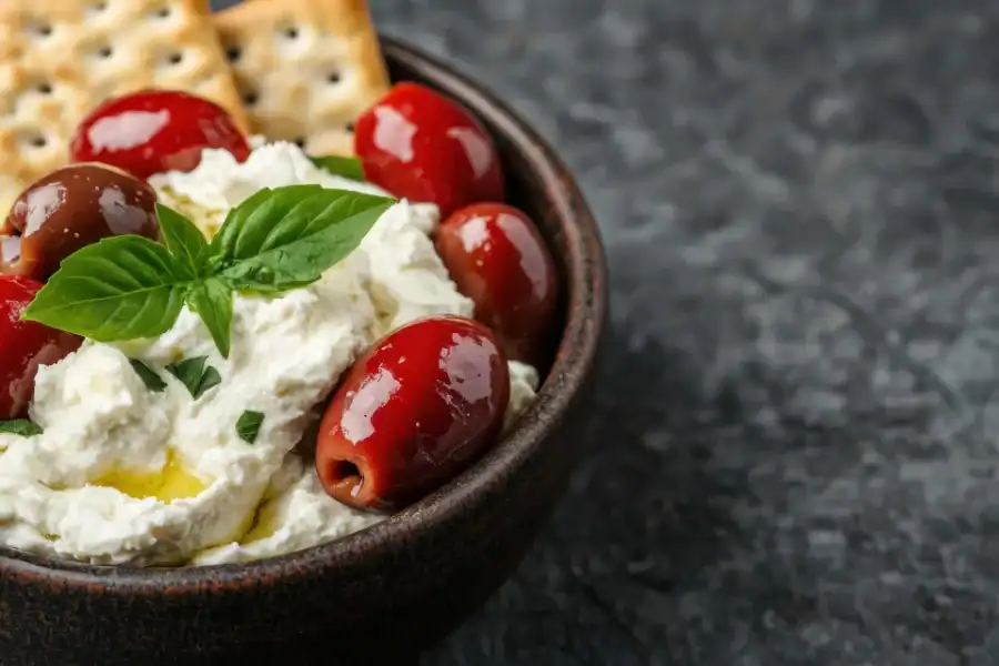 Whipped ricotta cheese dip topped with olives, herbs, and served with crackers