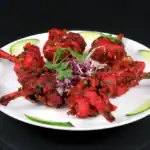 Spicy grilled chicken drumettes garnished with herbs and served with cucumber slices