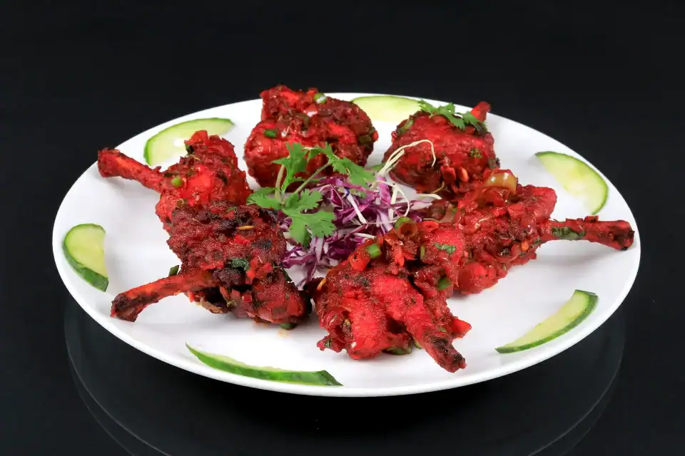 Spicy grilled chicken drumettes garnished with herbs and served with cucumber slices