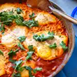 Indian Masala Shakshuka with poached eggs in spiced tomato sauce, topped with fresh cilantro