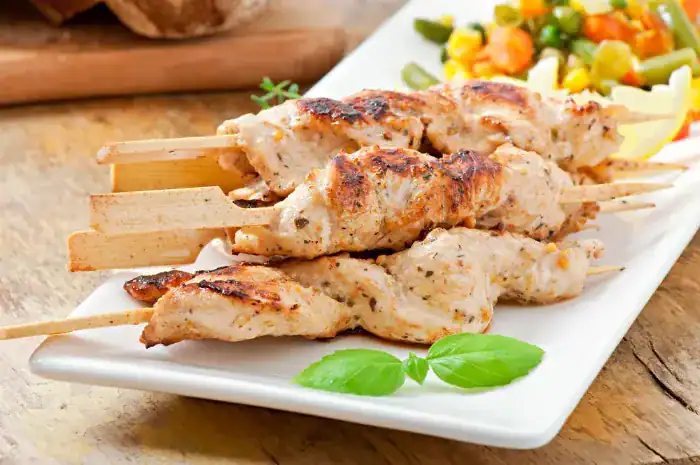 Grilled chicken kebabs served on a white plate with mixed vegetables
