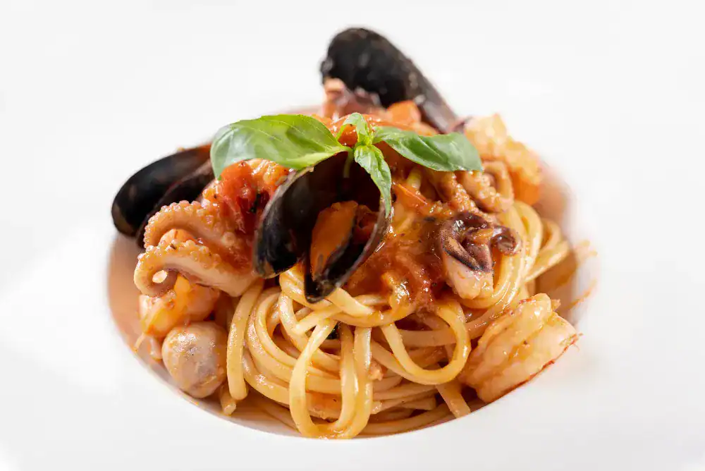 Spaghetti with squid, shrimp, mussels, and tomato sauce garnished with fresh basil