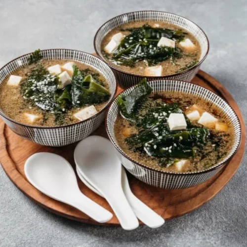 Bowls of miso soup with tofu, seaweed, and sesame seeds